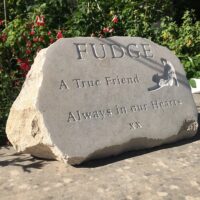 Limestone Boulder Pet Memorial for Fudge. It has a stretching cat motif